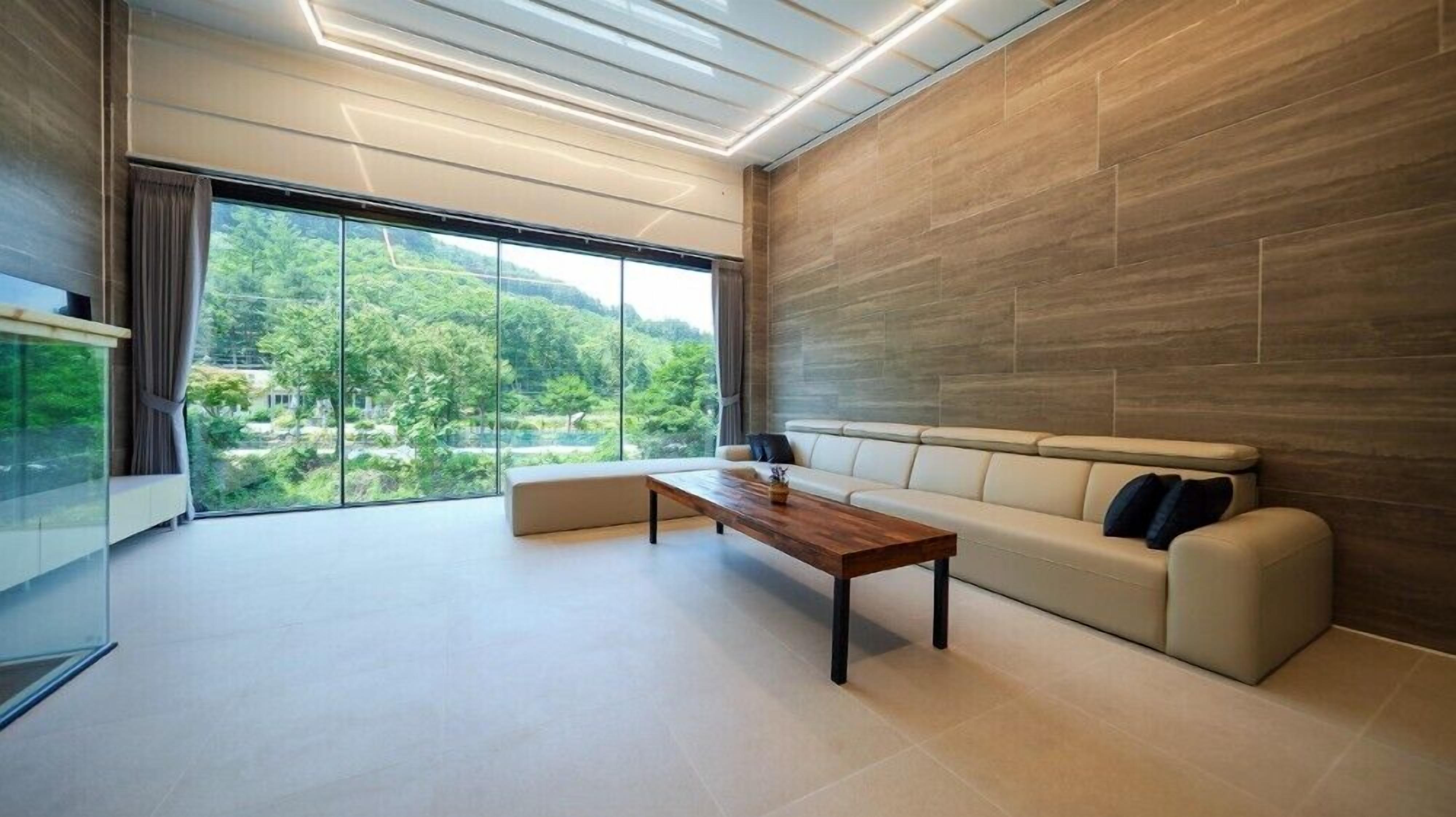 A modern living room with a large window, a sofa, and a wooden coffee table.