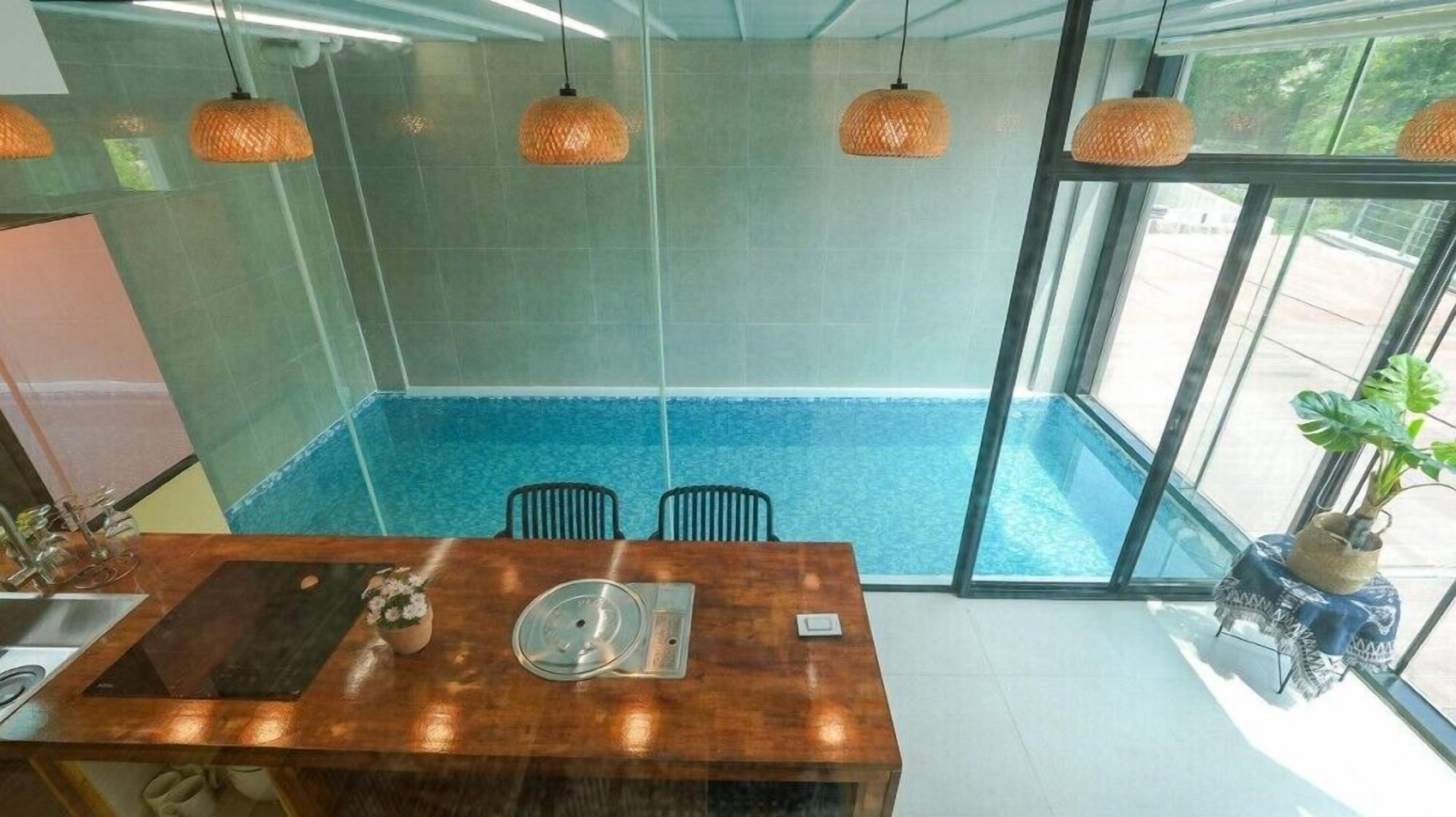 A modern dining area with a wooden table, two chairs, and a glass partition.