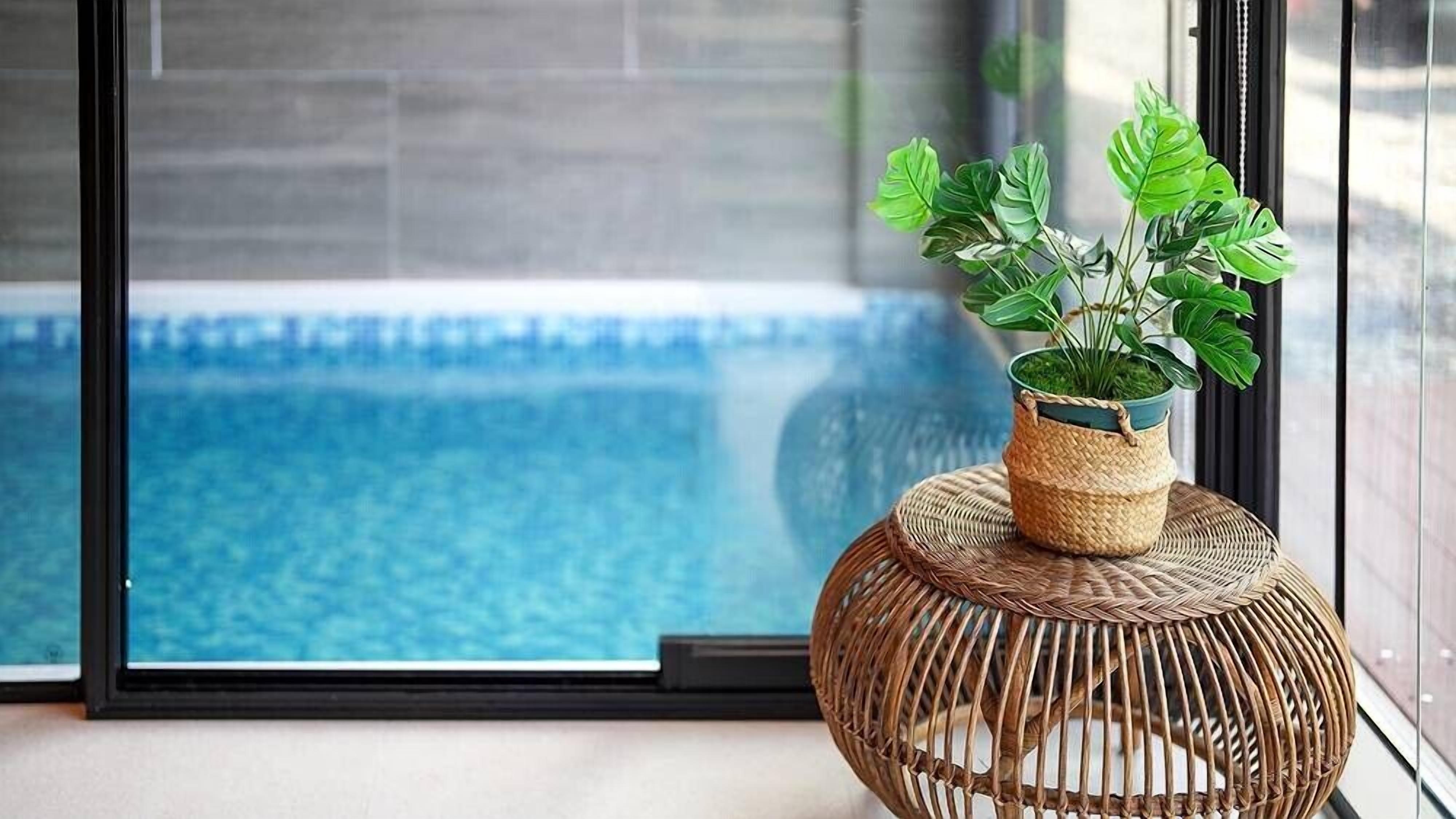 A room with a view of a swimming pool through a glass door.
