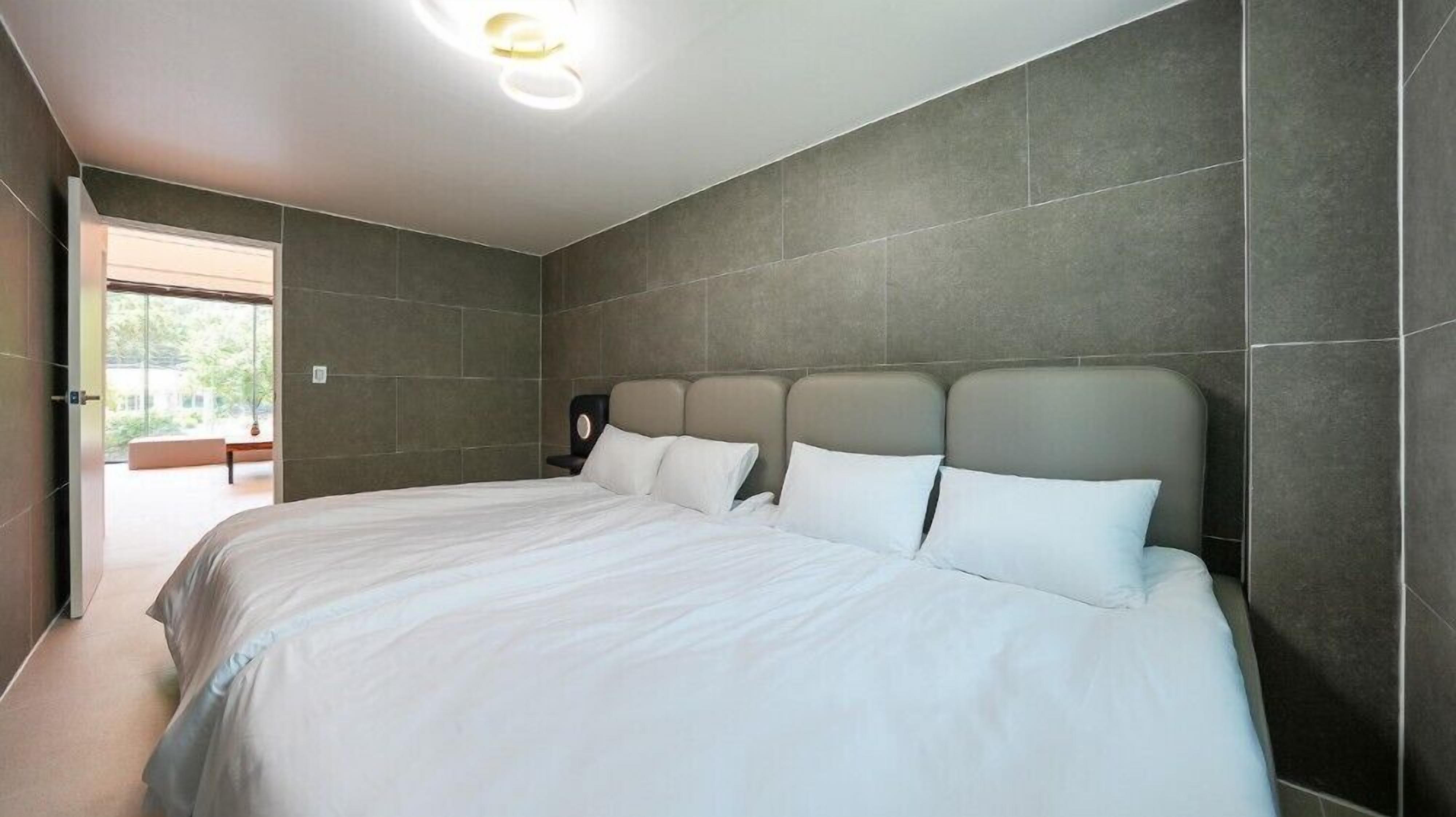 Un dormitorio moderno con una cama grande, paredes grises y una lámpara en el techo.