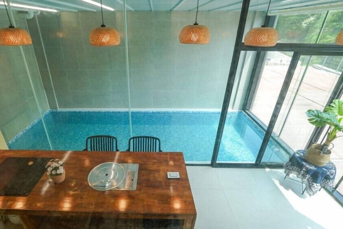Uma área de jantar moderna com uma mesa de madeira, duas cadeiras e um painel de vidro.