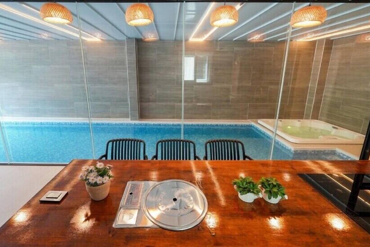 A conference room with a wooden table, chairs, a glass partition, a hot tub, and a pool.