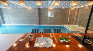 Un salón de conferencias con mesa de madera, sillas, panel de vidrio, bañera de hidromasaje y piscina.