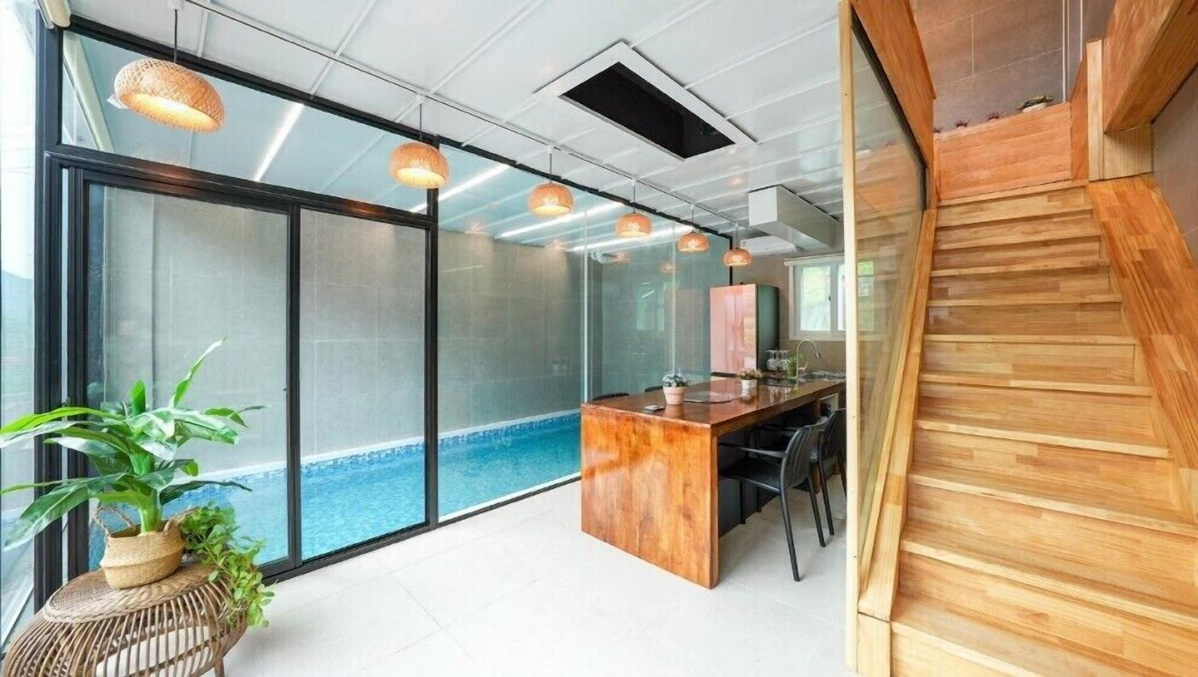 A modern office space with a glass wall, a wooden desk, and a small pool.