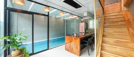 A modern office space with a glass wall, a wooden desk, and a small pool.