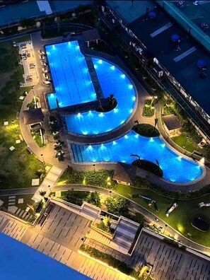 Vue aérienne d’un complexe de piscines comprenant plusieurs bassins, entouré d’espaces aménagés et de sentiers.