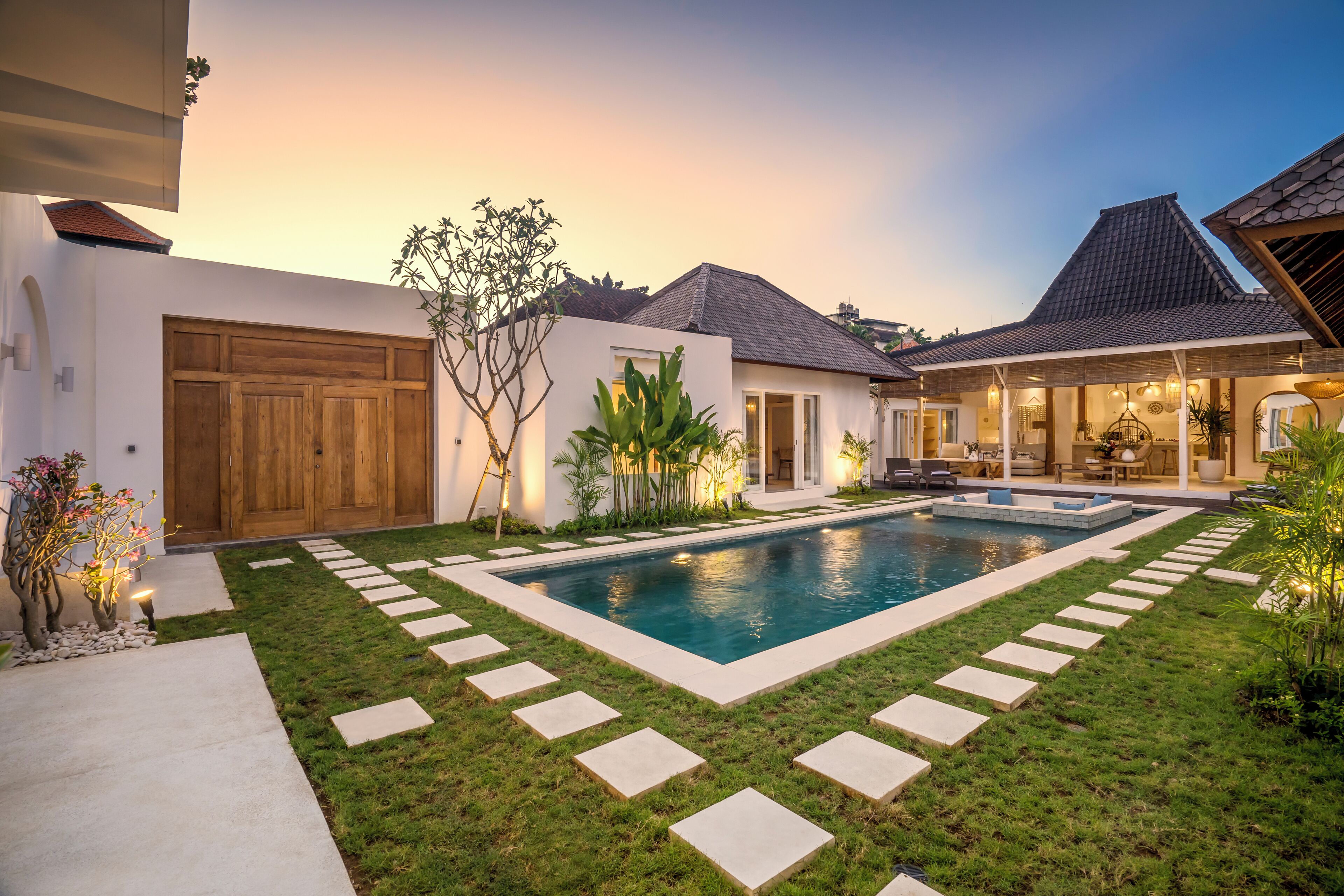 A modern house with a swimming pool, stone pathway, and well-maintained lawn.