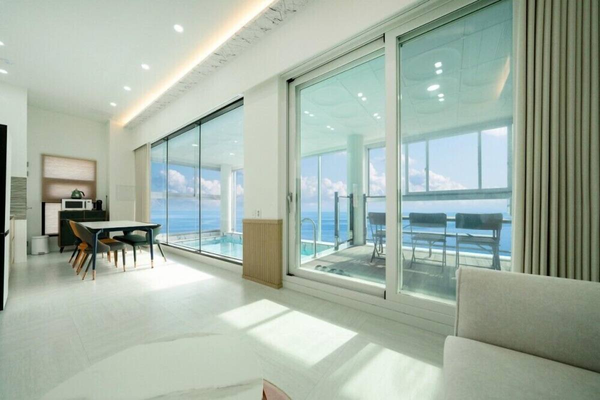 Ein modernes Hotelzimmer mit einer großen Schiebeglasdoor zum Balkon mit Meerblick.