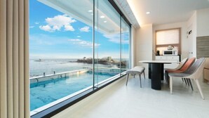 Una habitación moderna con un gran ventanal con vistas a una piscina y al mar.