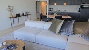 A modern living room with a grey sofa, a coffee table, and a dining area with a table and chairs.