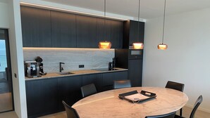 A modern kitchen with dark cabinetry, a marble island, and pendant lighting.