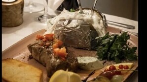 A plate of food with a stuffed grape leaf, a piece of meat, and some greens. - Hotel Restaurant Hillmers Hoff (Undeloh)