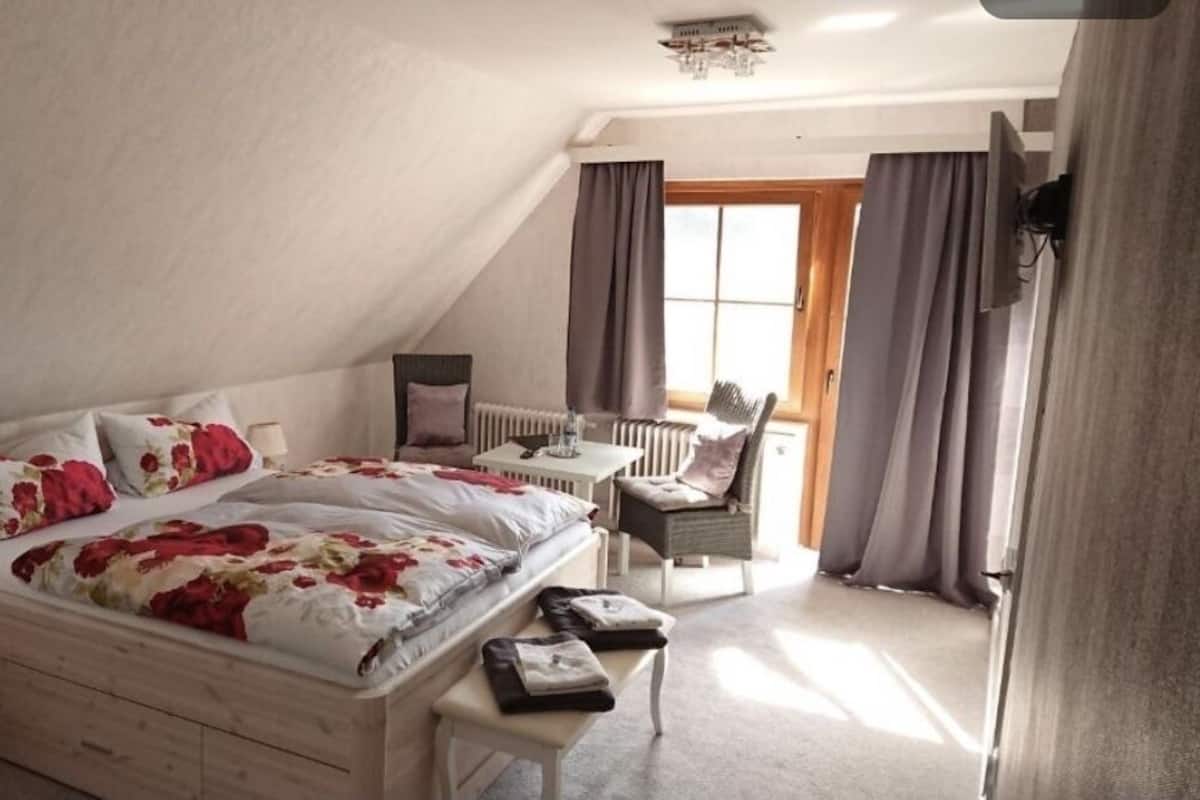 A bedroom with a large bed, a desk, and a chair.