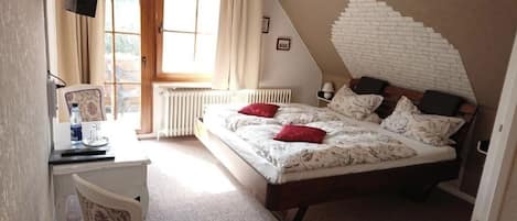 Quarto com cama, escrivaninha, cadeira e janela com cortinas.