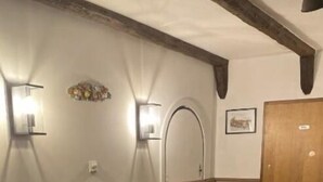 A hallway with wooden flooring, a white wall with a decorative light fixture, and a wooden door. - Hotel Restaurant Hillmers Hoff (Undeloh)