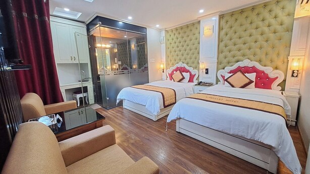 Habitación de hotel con dos camas, una zona de estar, un espejo y una mesita.