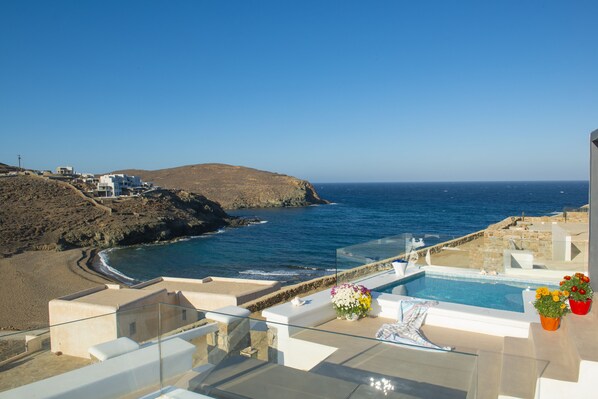 A coastal hotel with a pool, beach view, and a rocky landscape. - Myrsini's Luxury Suites (Mykonos)