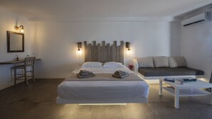A modern hotel room with a large bed, bedside tables, a desk, and a sofa. - Myrsini's Luxury Suites (Mykonos)
