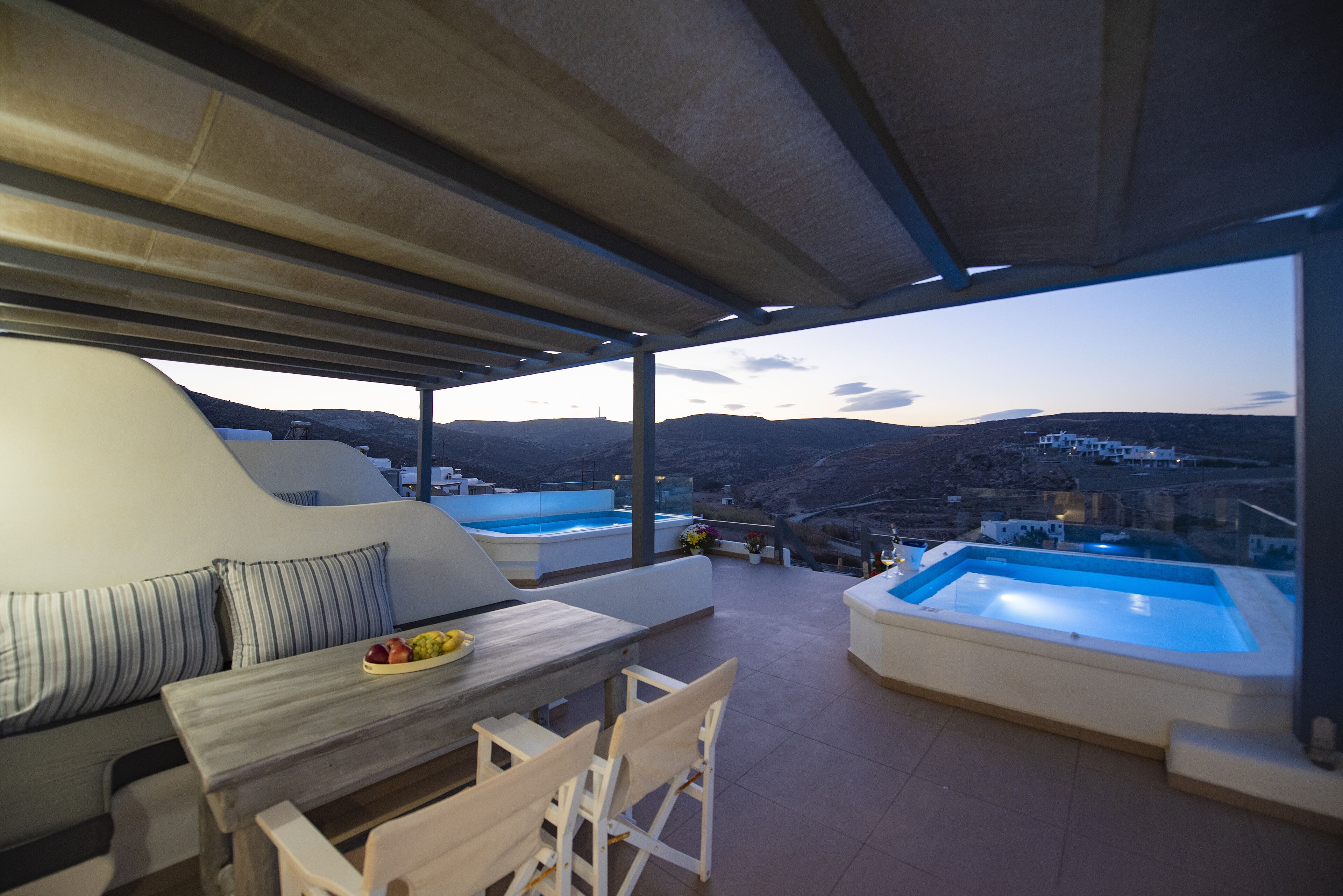 A covered outdoor area with a pool, seating, and a view of the landscape.