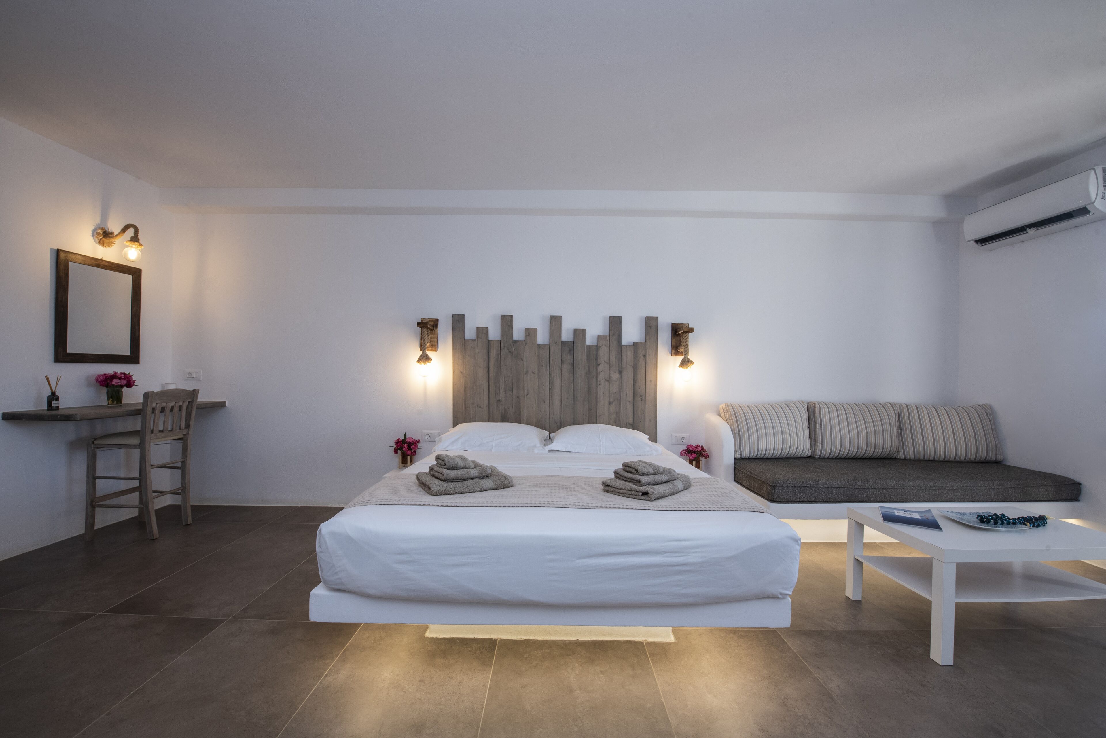 A modern bedroom with a large bed, bedside tables, a desk, and a sofa.