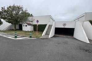 Un bâtiment avec une entrée de garage, un petit abri de jardin et un vélo garé à proximité.