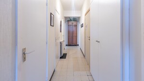 A narrow hallway with white walls, a tiled floor, and doors on both sides leading to rooms. - Ground floor apartment with sea view and garage (Middelkerke)