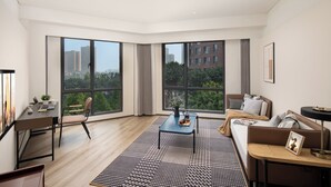 A modern living room with a large window, a sofa, a coffee table, and a desk with a chair. - Citadines Connect Chayuan Chongqing (Chongqing)