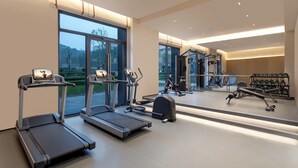 A modern gym with treadmills, a rowing machine, and a weight rack. - Citadines Connect Chayuan Chongqing (Chongqing)