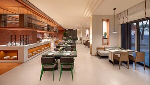 A modern dining area with a long table, green chairs, and a buffet counter with food items. - Citadines Connect Chayuan Chongqing (Chongqing)
