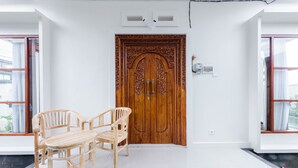 Une pièce avec une porte en bois, des murs blancs, un sol carrelé et une table entourée de chaises.