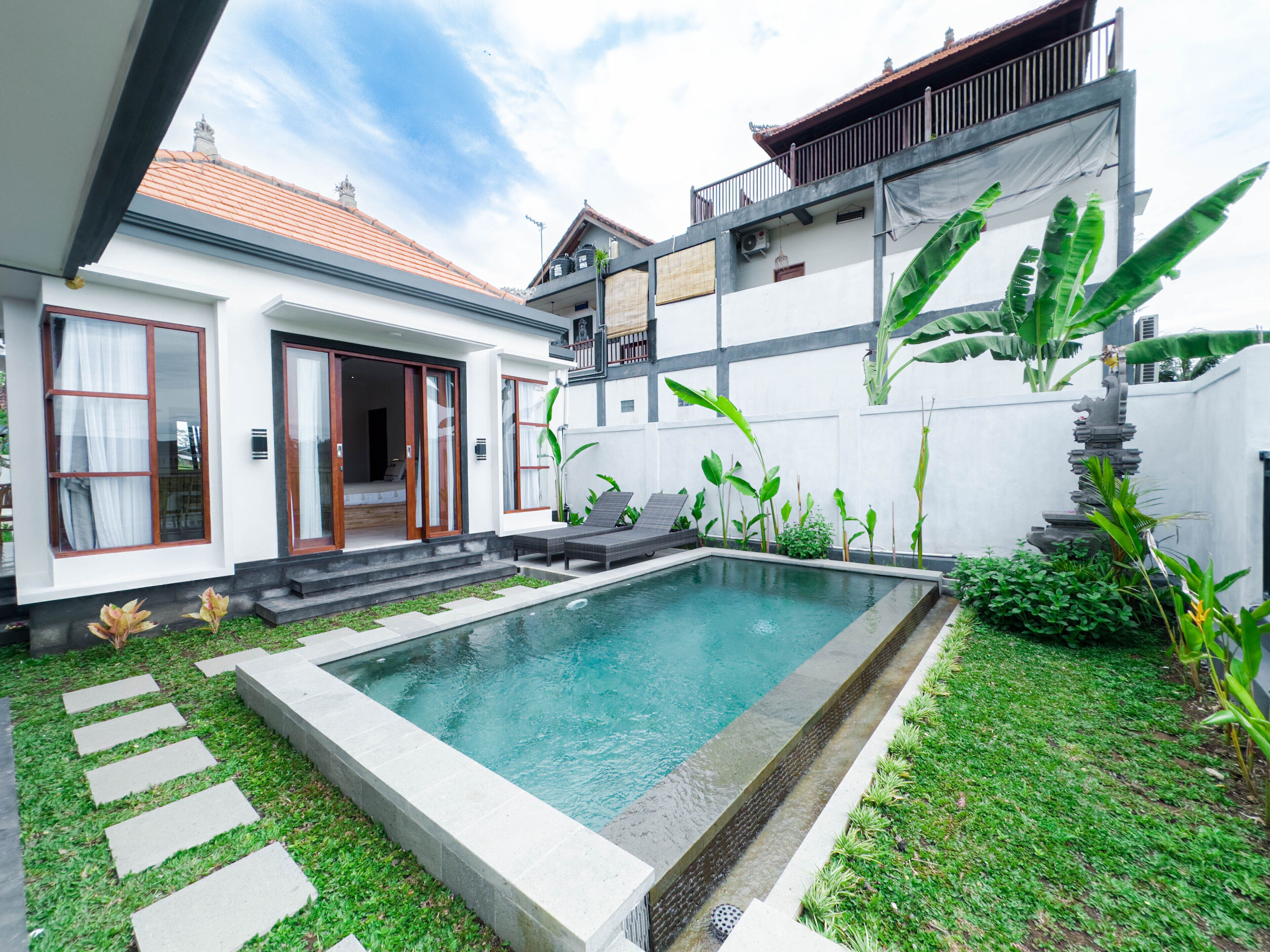 A modern house with a swimming pool, a covered patio, and lush greenery.