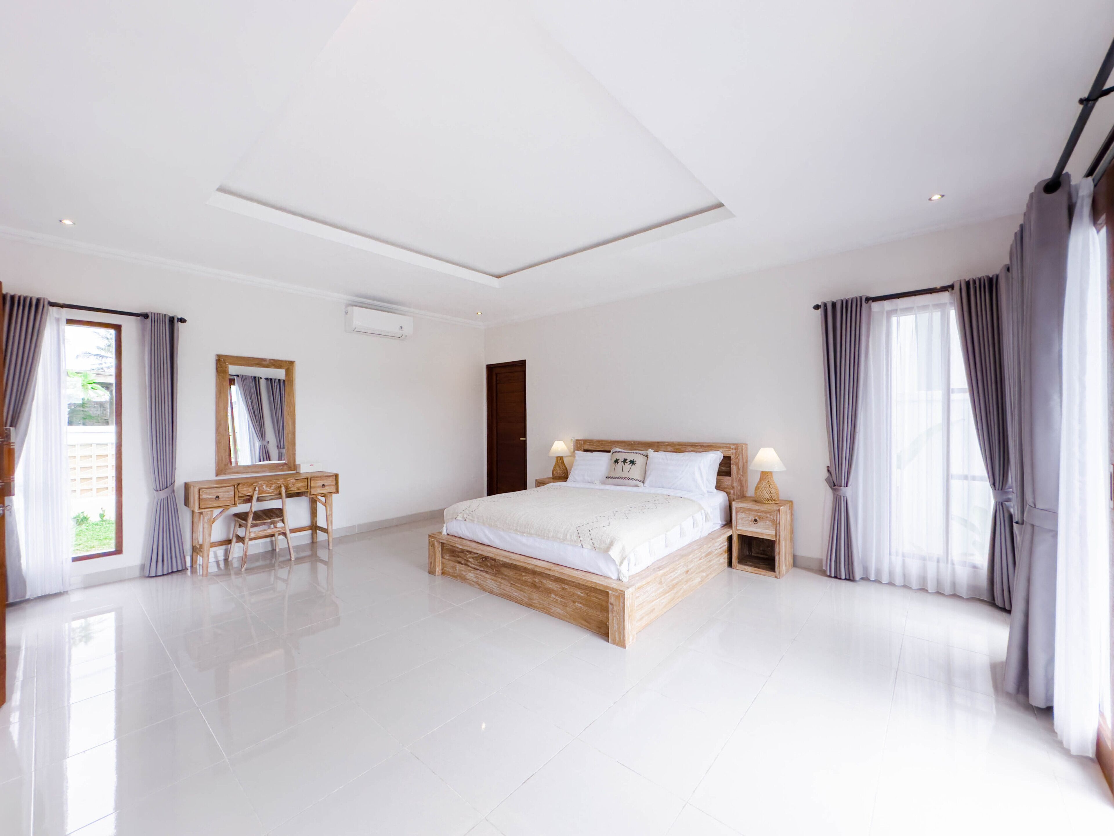 A spacious bedroom with a large bed, a wooden dresser, a desk, and a chair.