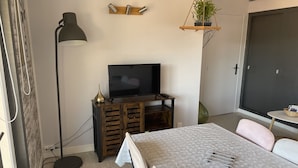 A modern living room with a TV, wooden cabinet, and a dining table.