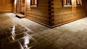 Un edificio moderno de madera con techo inclinado y ventanas amplias, iluminado con luz cálida.