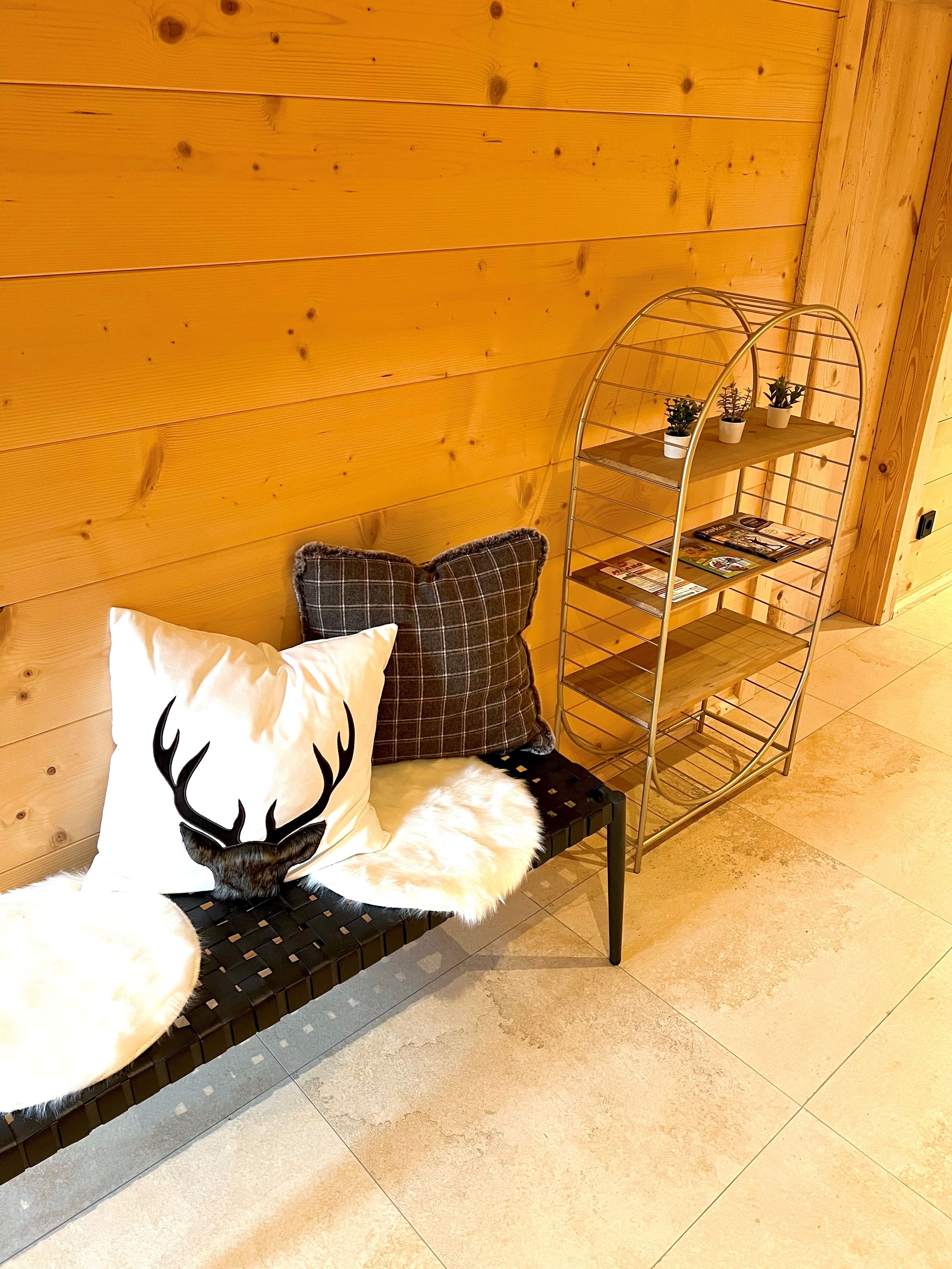 A wooden bench with a metal shelf unit against a wooden wall.