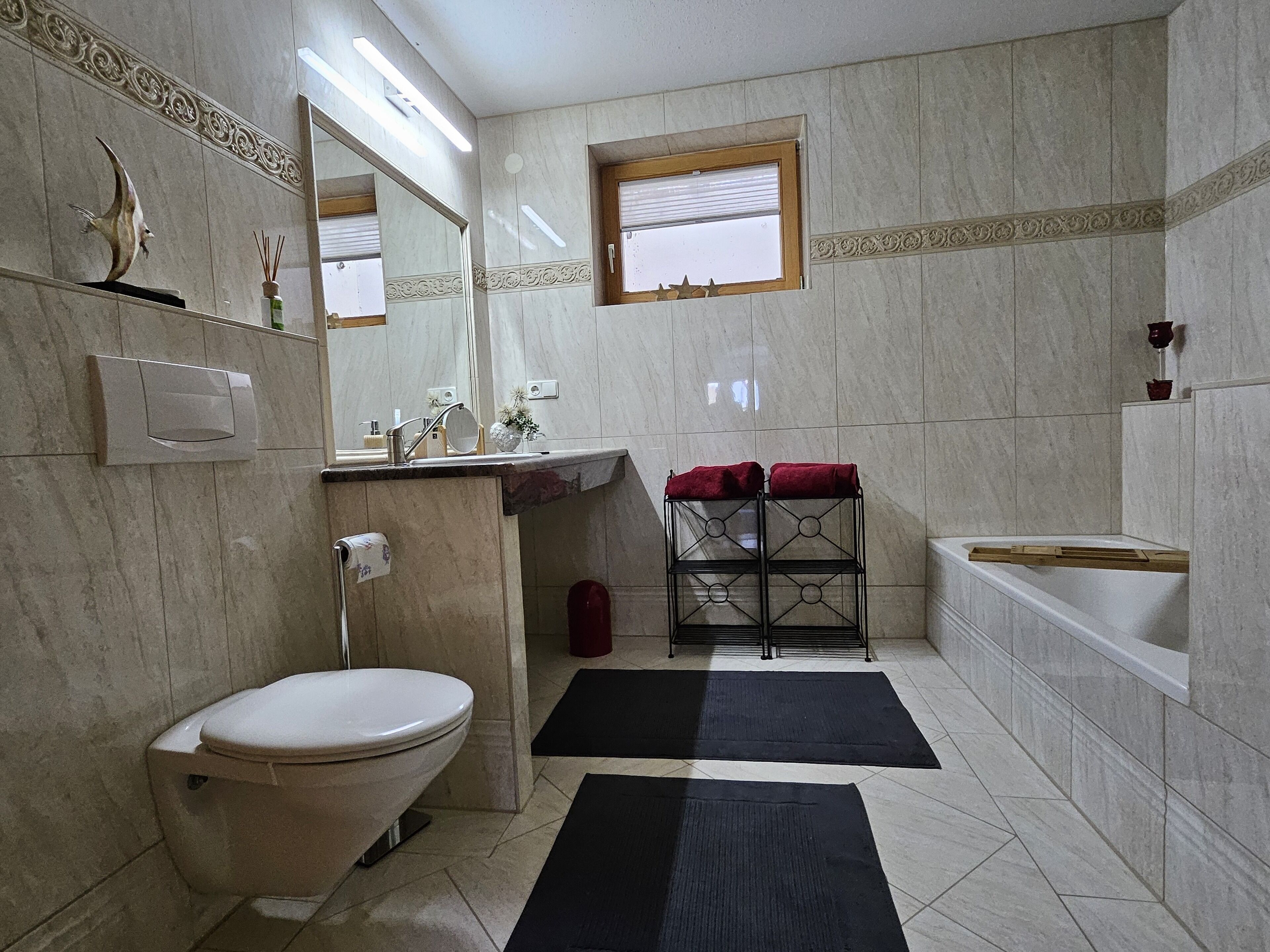 A bathroom with a toilet, sink, mirror, and a window.