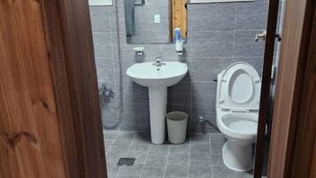 Un baño con lavamanos blanco, inodoro y un pequeño cubo de basura.