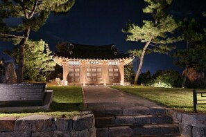A traditional Korean-style building with a tiled roof and wooden doors, surrounded by a stone pathway and trees. - dong hae ae pension (Donghae)