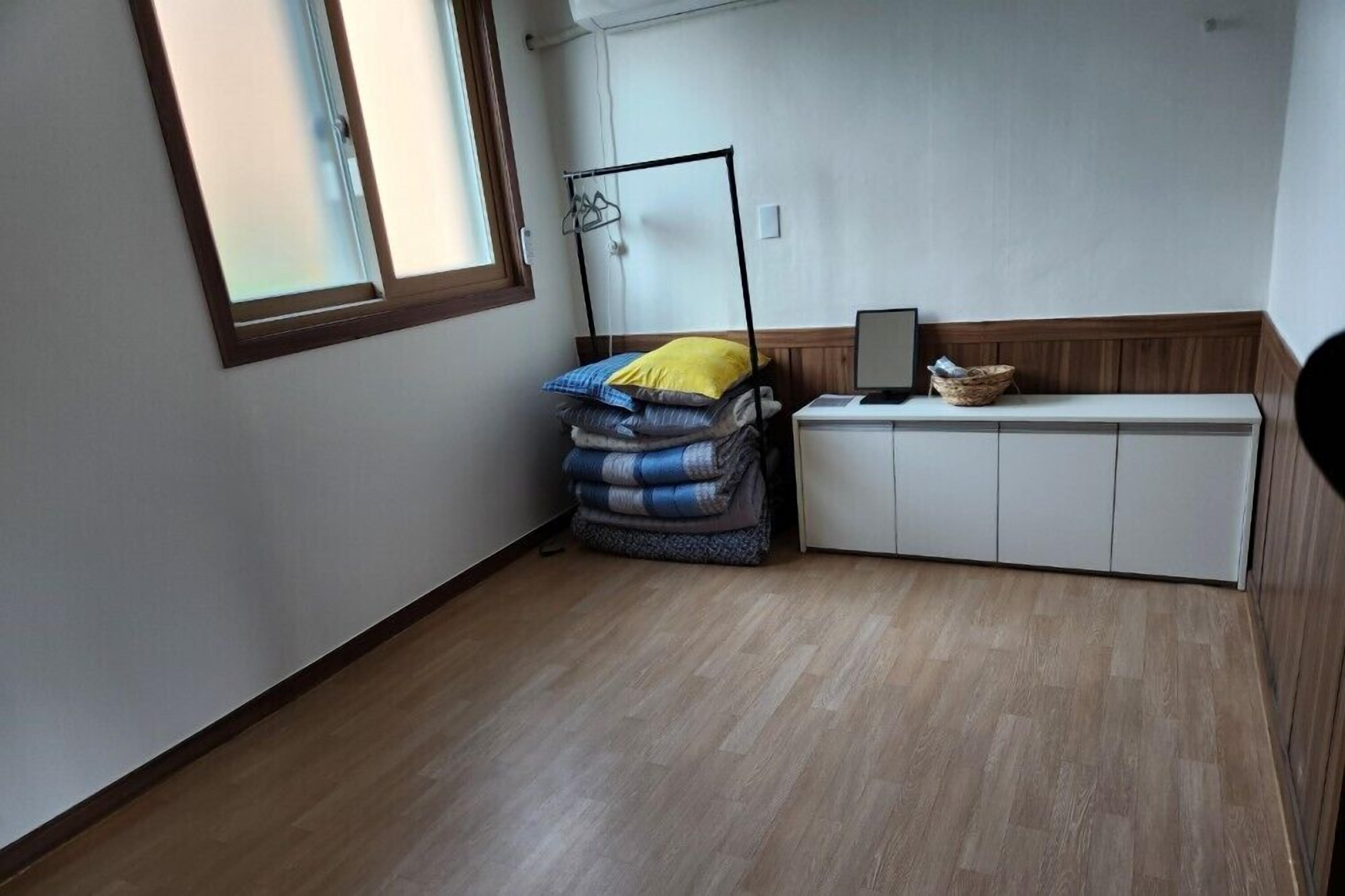 A small room with a bed, a bedside table, a window, and a cabinet.