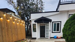 Una casa moderna con fachada blanca, una valla de madera y un pequeño jardín.