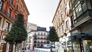 Vista de una calle con edificios, un carril para taxis y un paso de peatones.