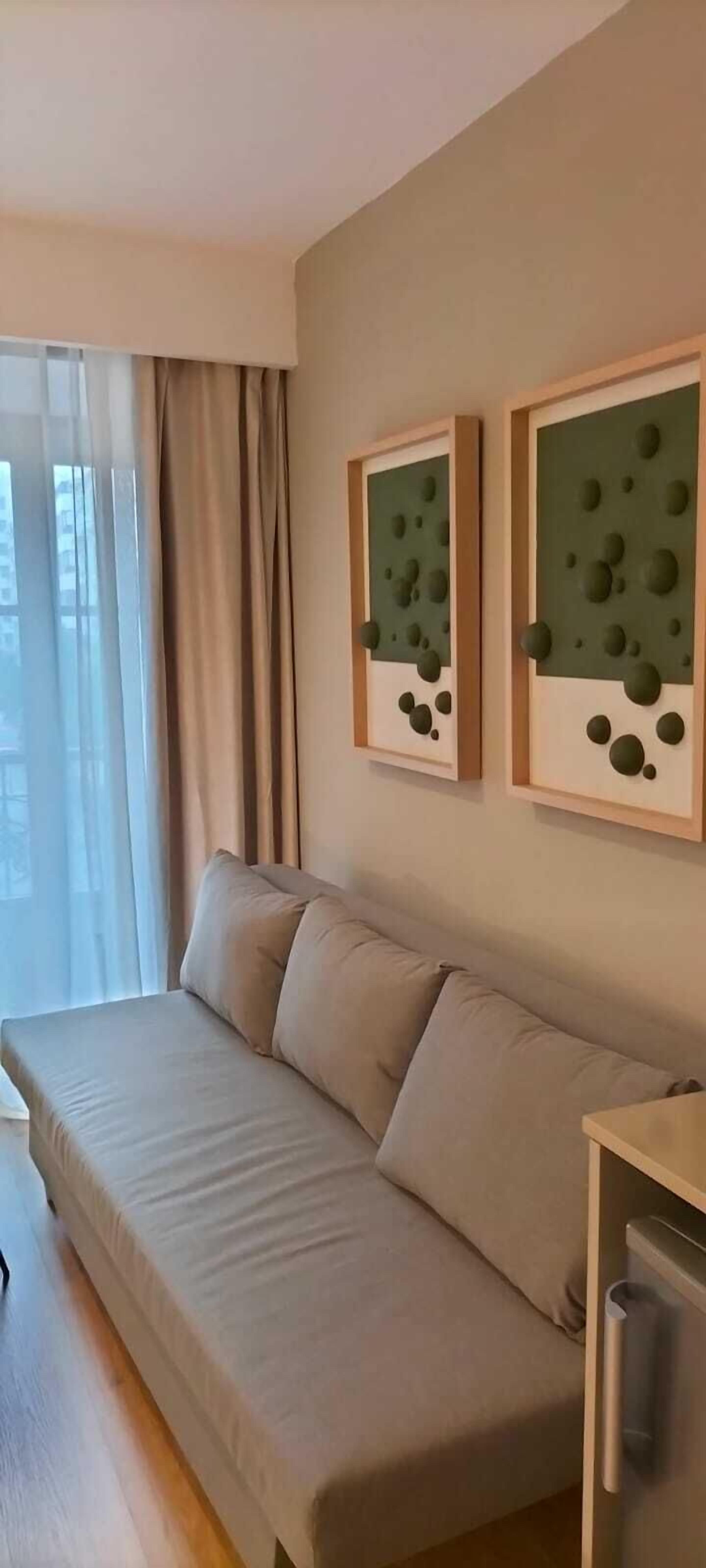 Una sala de estar moderna con un sofá color beige, una mesita de madera y dos obras de arte abstractas en la pared.