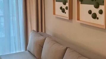 Una sala de estar moderna con un sofá color beige, una mesita de madera y dos obras de arte abstractas en la pared.