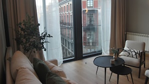 Una sala de estar moderna con un ventanal grande, un sofá, un sillón y una mesita.