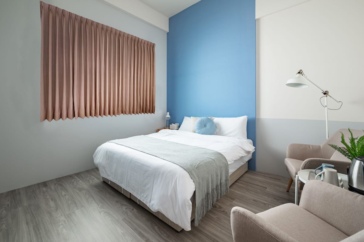 A modern bedroom with a bed, a nightstand, a lamp, and a chair.