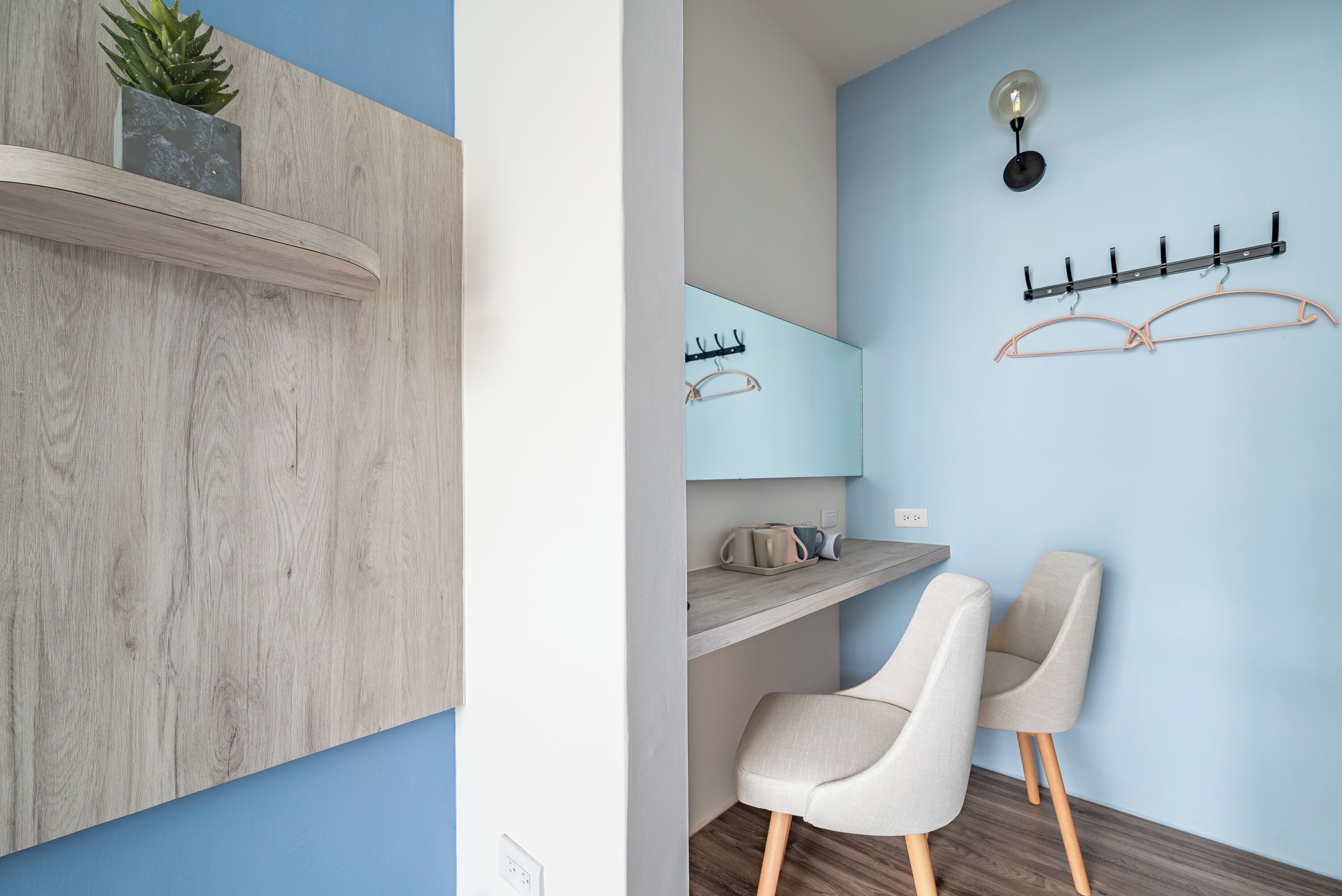 A modern bathroom with a wooden vanity, a mirror, a towel rack, and a plant on the shelf.