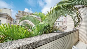 A balcony with a stone ledge, green plants, and a view of buildings. - Penghu Yun Ting Style Inn (Magong)