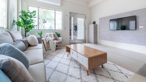 A modern living room with a sofa, coffee table, and a TV mounted on the wall. - Penghu Yun Ting Style Inn (Magong)