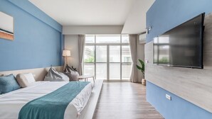 A modern hotel room with a large bed, a TV mounted on the wall, and a view of the outdoors through a large window. - Penghu Yun Ting Style Inn (Magong)
