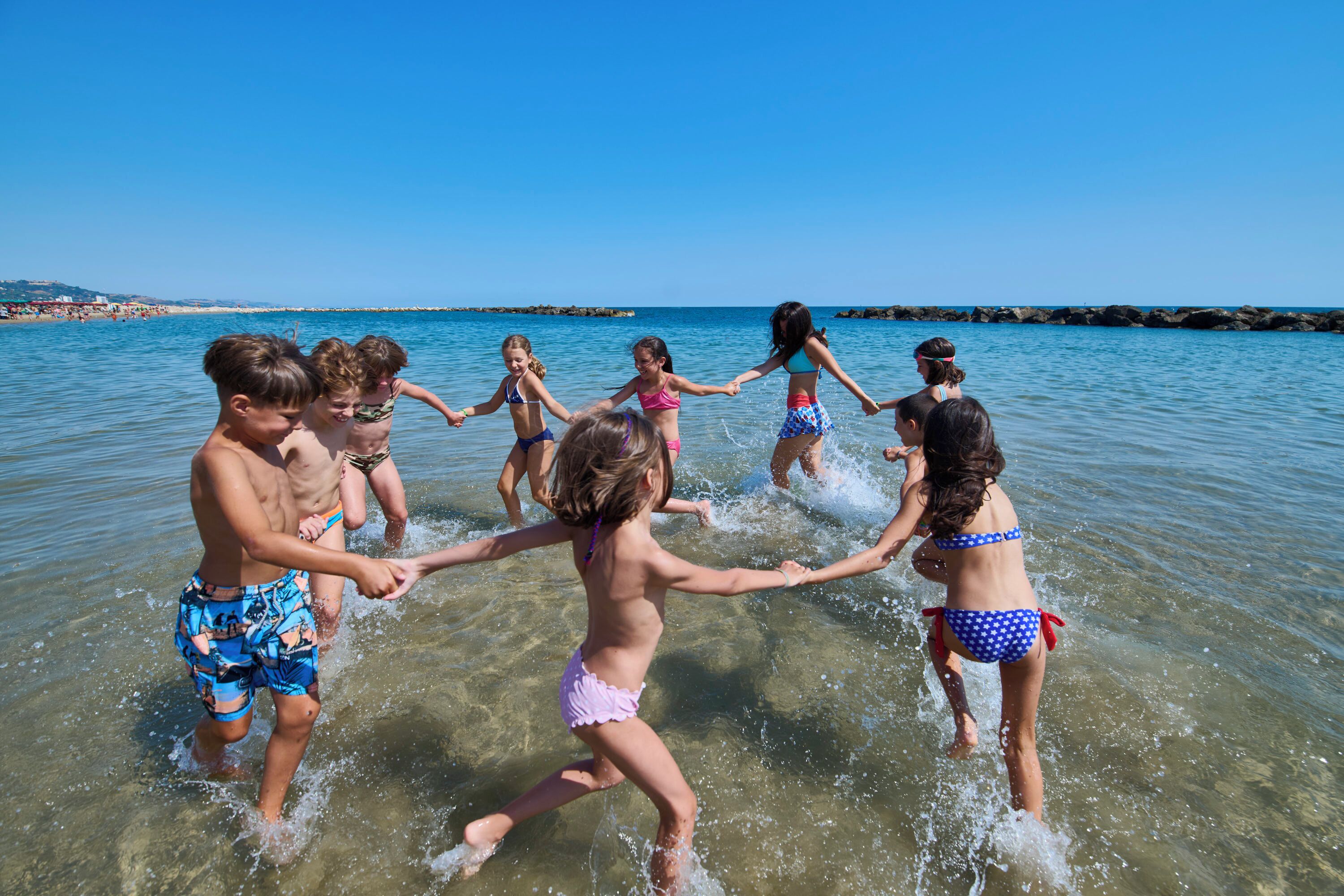 Un grupo de niños jugando en aguas poco profundas en una playa.